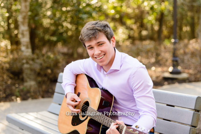 Senior guy playing a guitar on a park bench