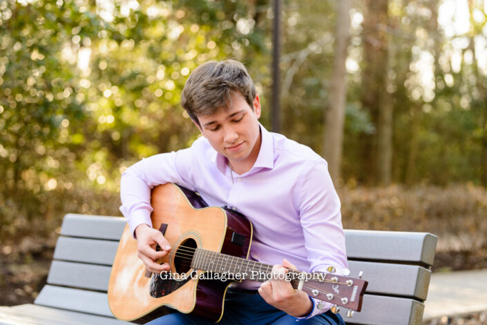 Senior guy playing a guitar on a park bench